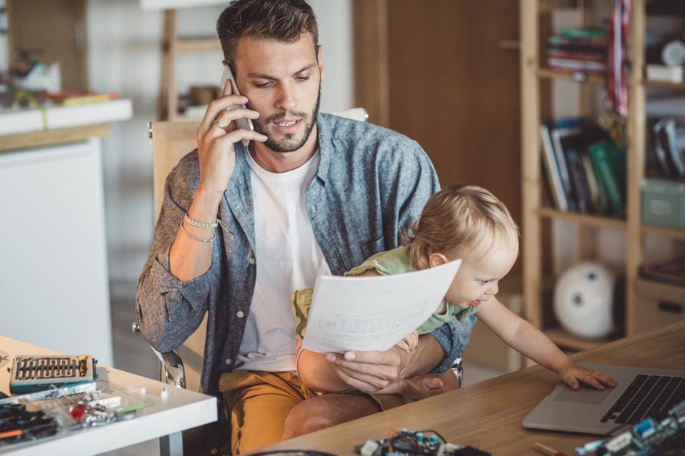 Un parent au téléphone travaille tout en s'occupant de son bébé