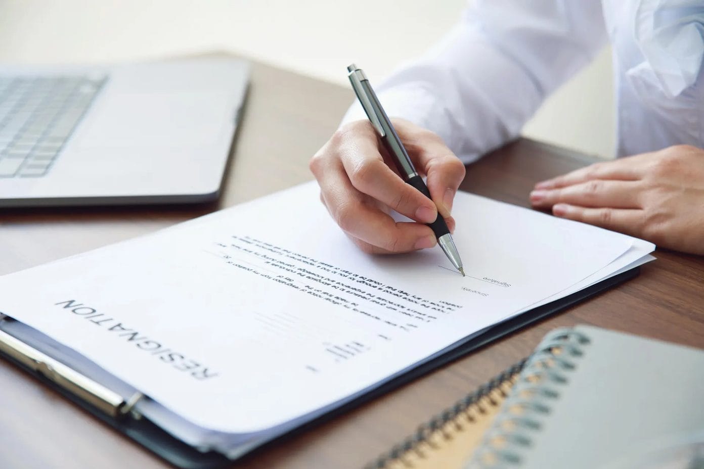 Lettre de démission posée sur un bureau à côté d'un stylo, bandeau de l'article Gesti'Paie sur la démission