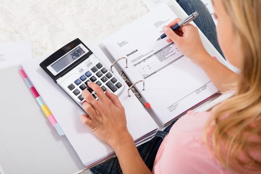 Personne vérifiant des documents avec une calculatrice, illustrant la retenue pour mise à pied